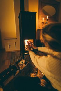 warming hands in front of wood burning stove